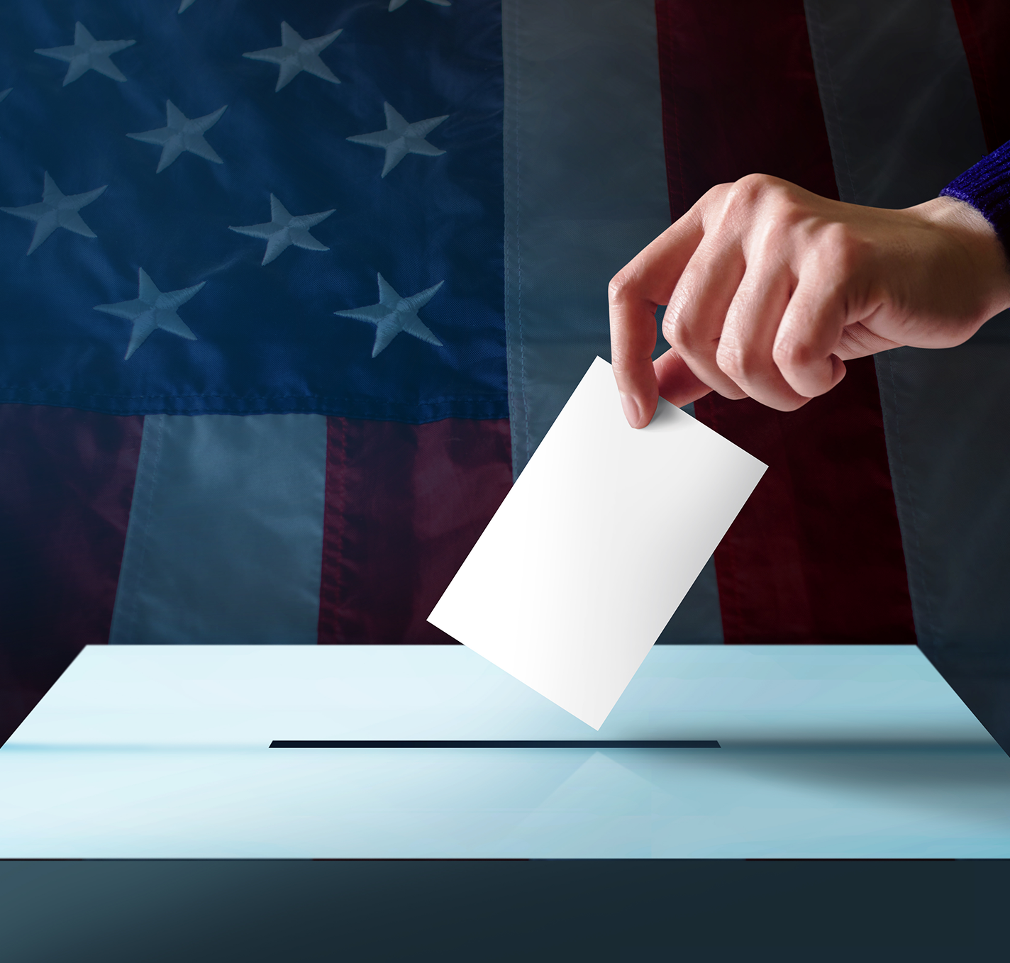 Hand placing ballot in box, American flag.